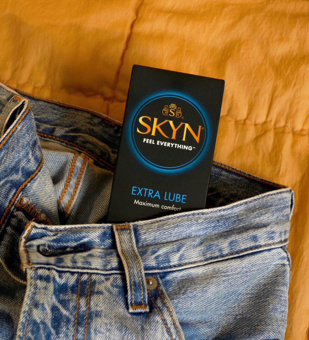 SKYN Extra Lube condom box inside a pair of blue jeans