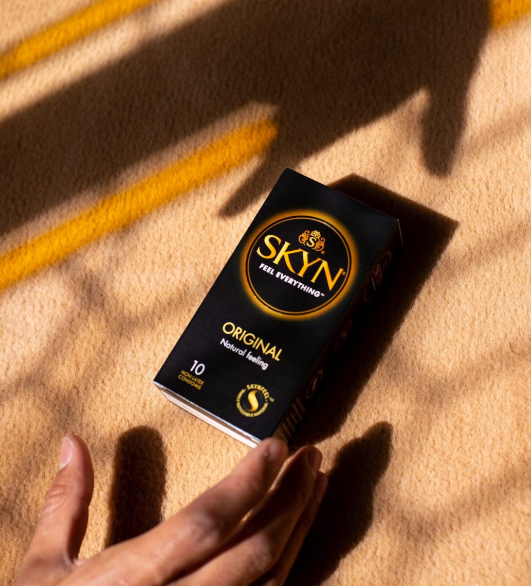 Hand reaching a box of SKYN Original condom box