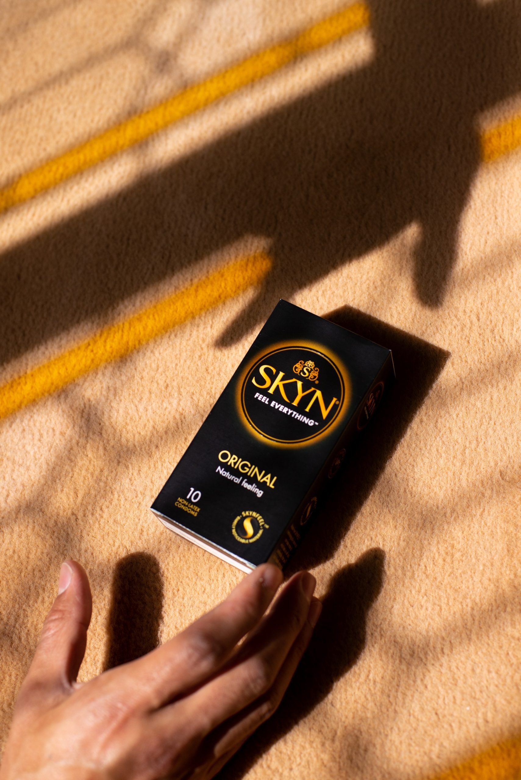 Hand reaching a box of SKYN Original condom box