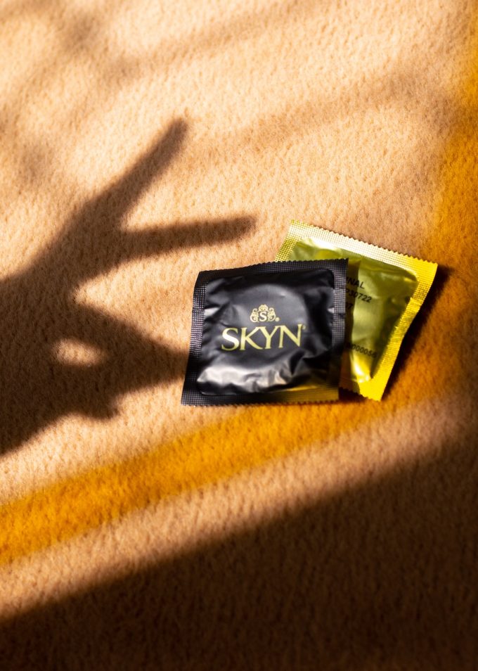 Hand shadow over two SKYN condom sleeves