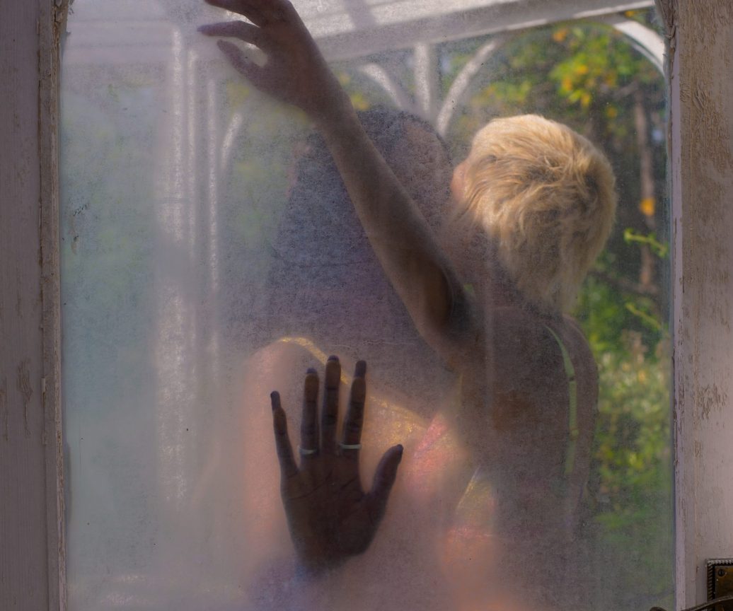 Two girls kissing seen from a frozen glass door