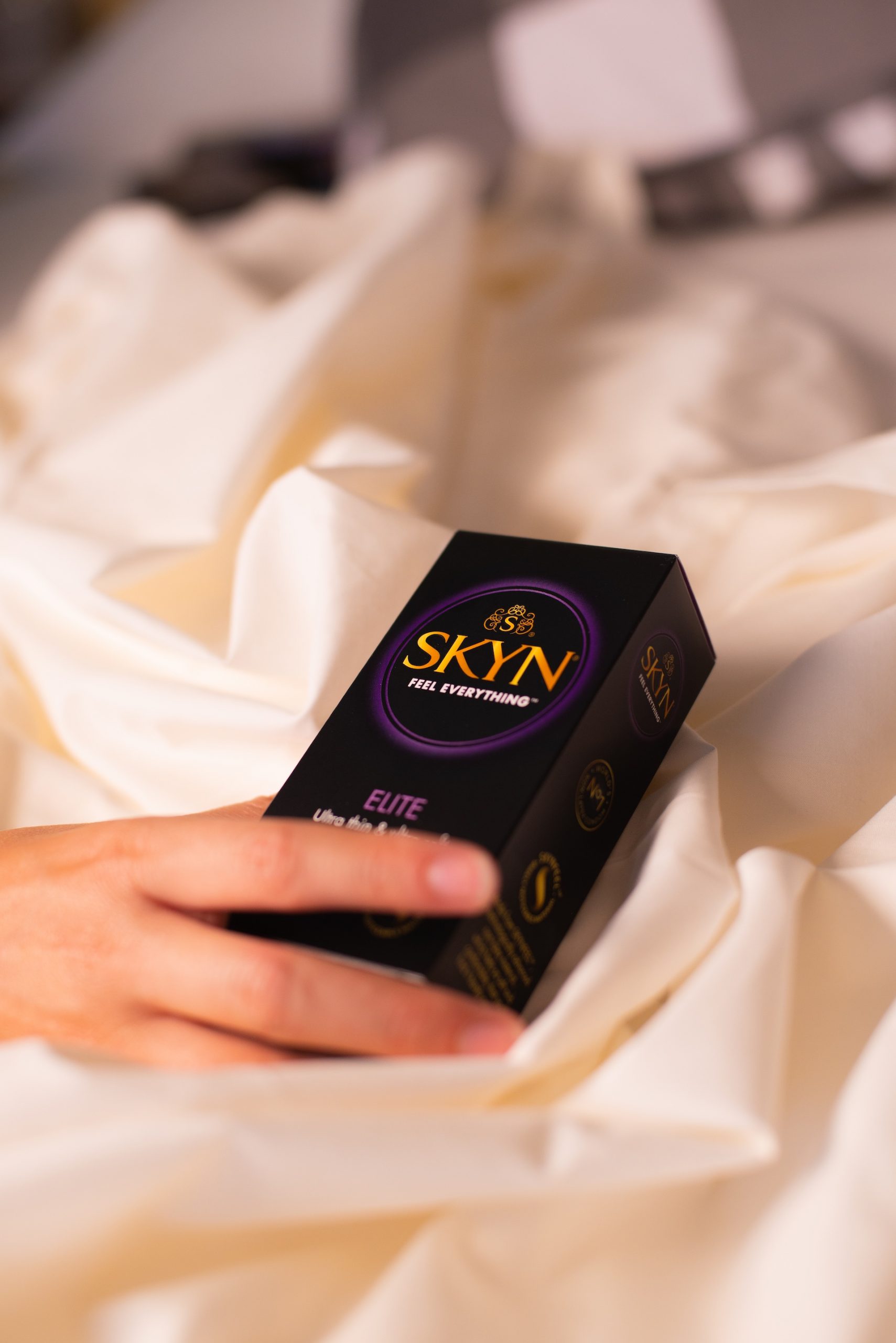 Hand reaching over a SKYN Elite condom box